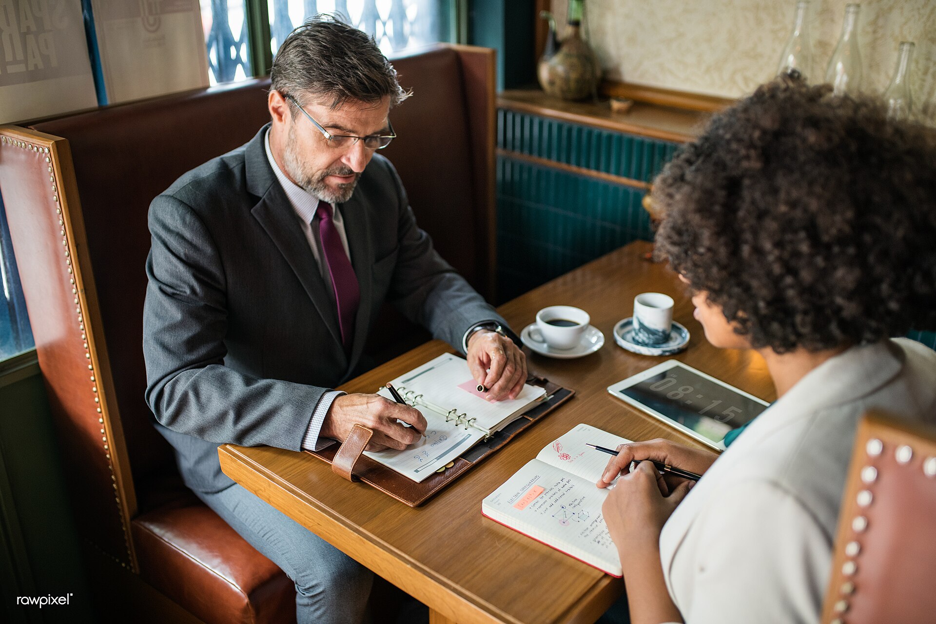 Two business people reviewing notes together at a cafe table