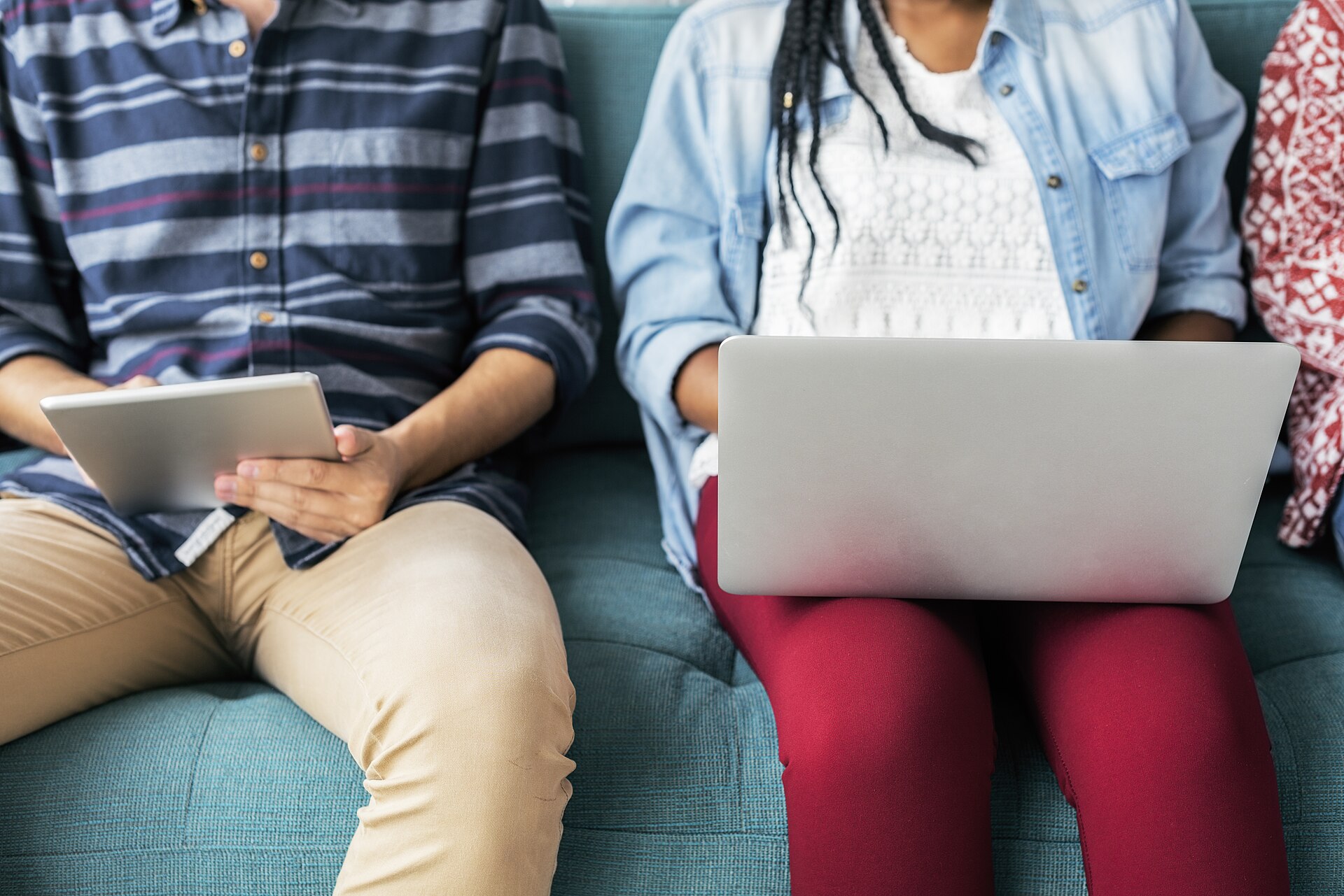 Two people sitting together, one holding a tablet, studying